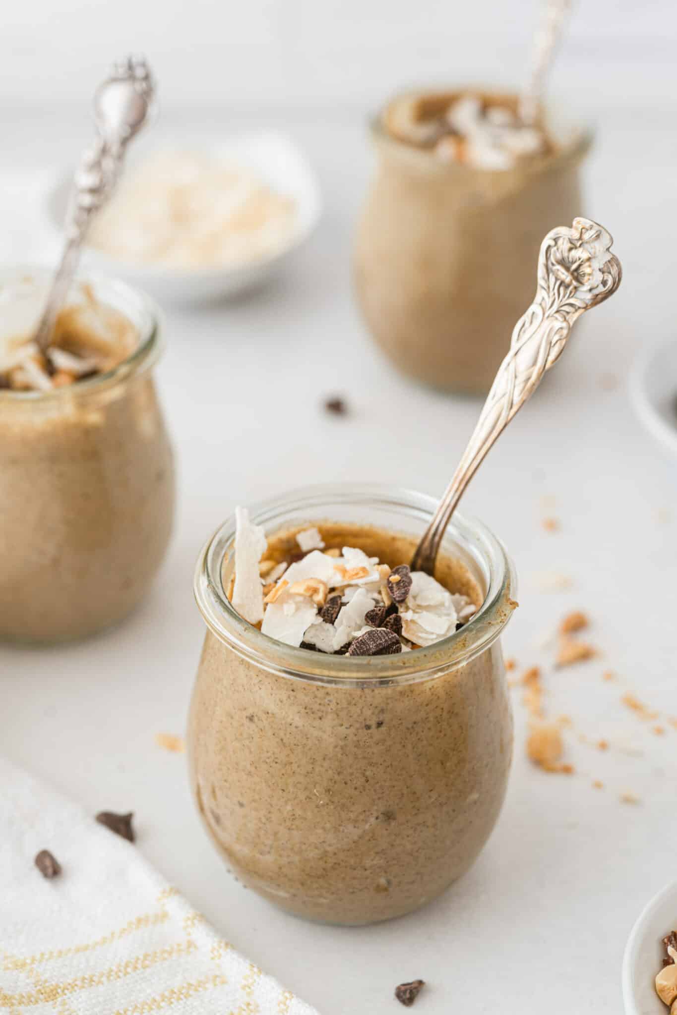 Small jars of PB chia pudding topped with chocolate and coconut.