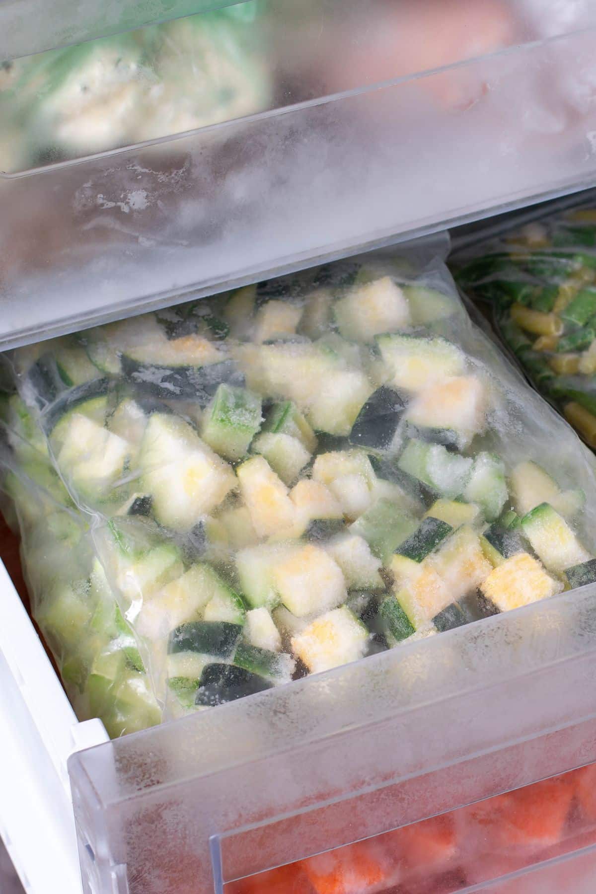 Diced zucchini frozen in a baggie in a freezer drawer.