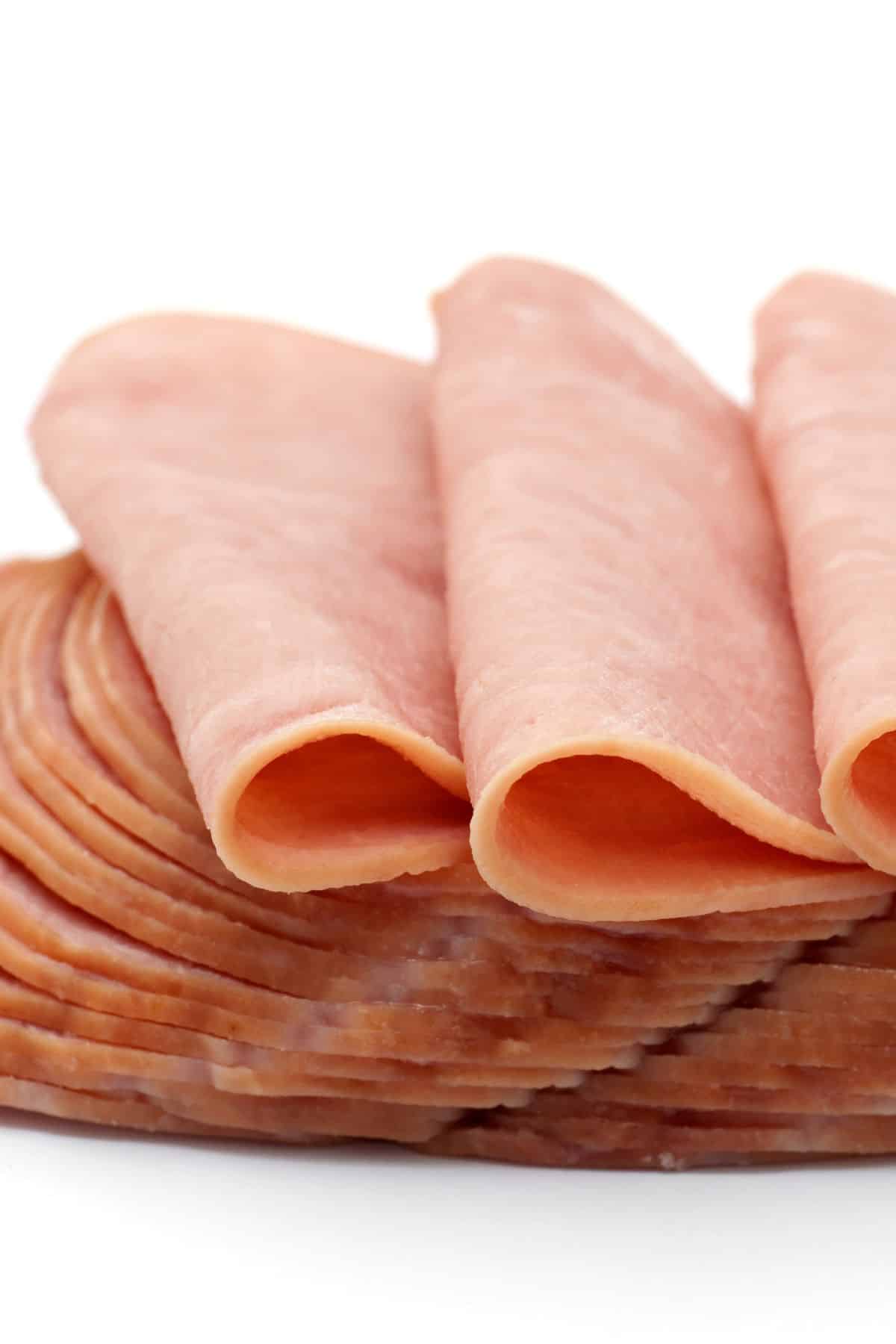 Sliced deli meats in a stack on a white surface.