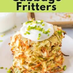 Cabbage fritters stacked on a white plate, topped with sour cream.