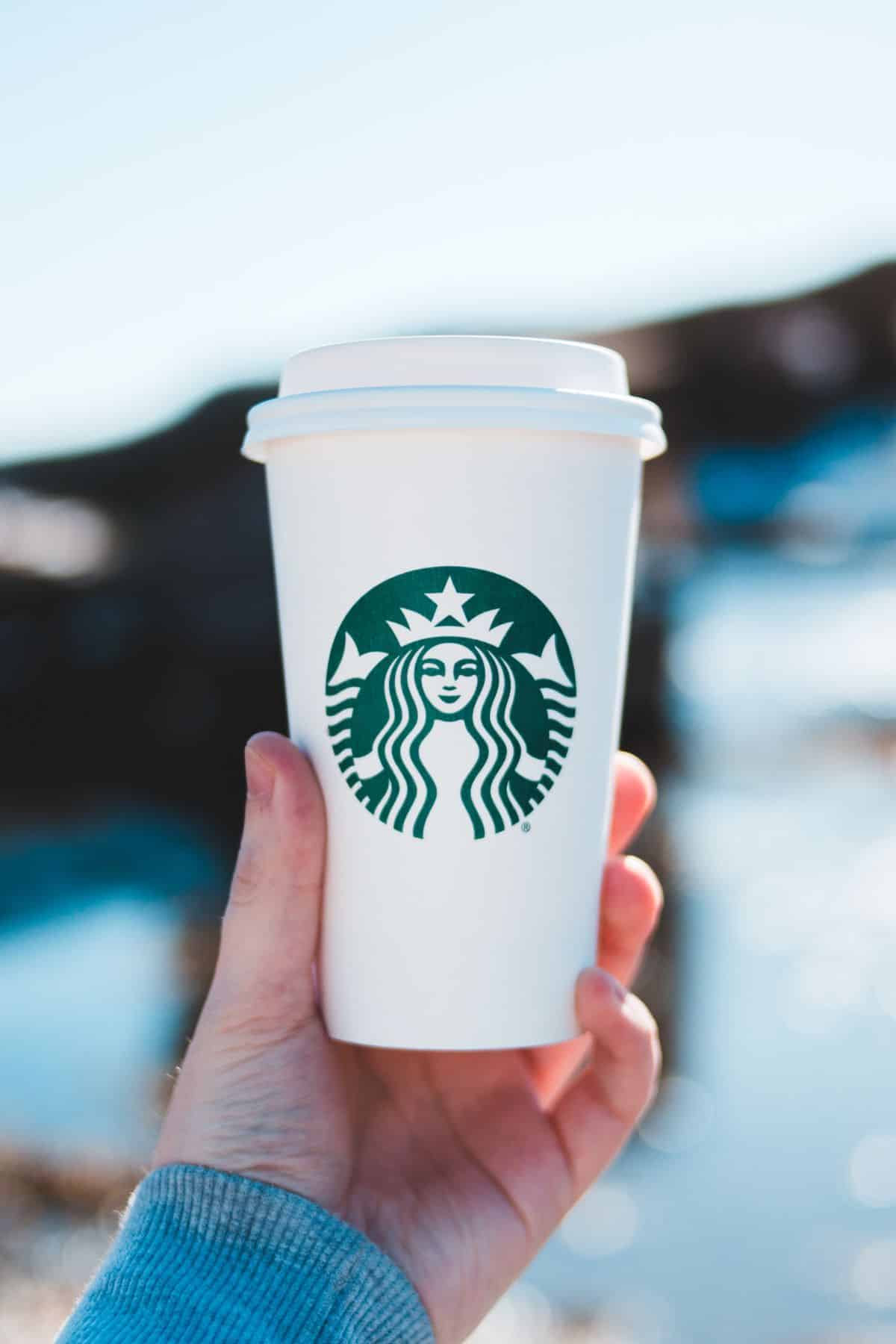 a person holding a Starbucks cup.