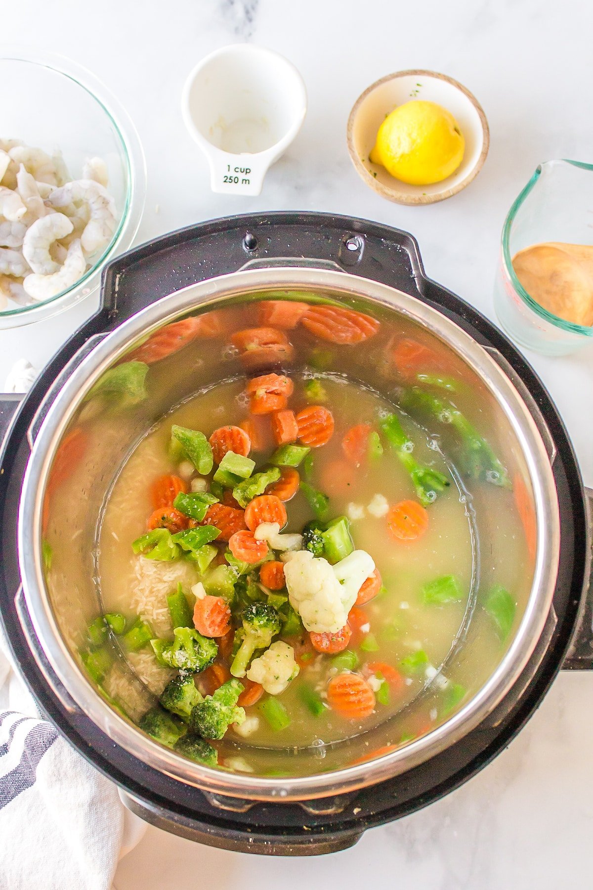 Broth and frozen veggies in the liner of an Instant Pot.