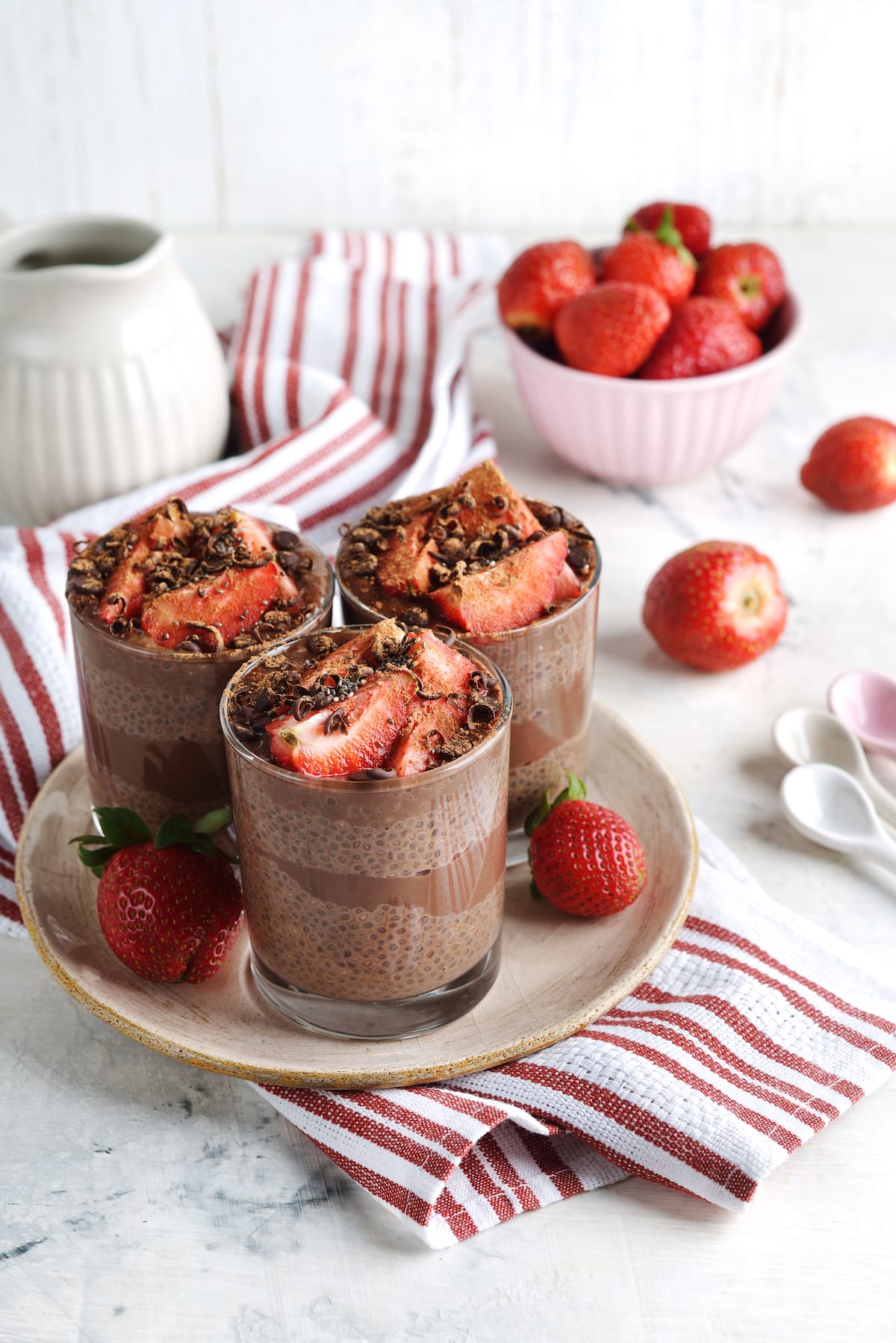 group of chia puddings with chocolate and strawberries on tabletop.