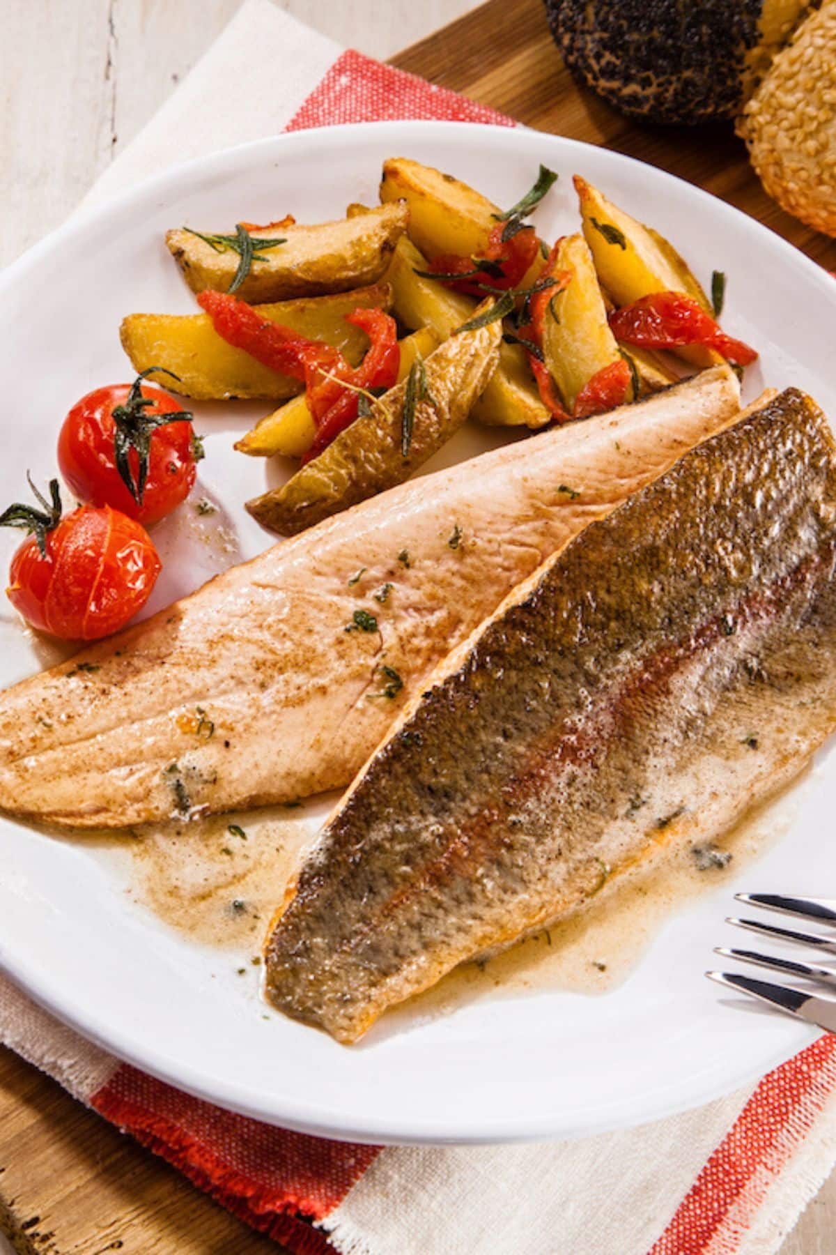 cooked trout on a plate with vegetables.