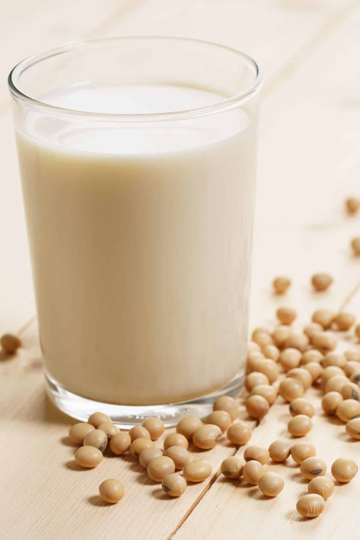 soy milk in a glass surrounded by soy beans.