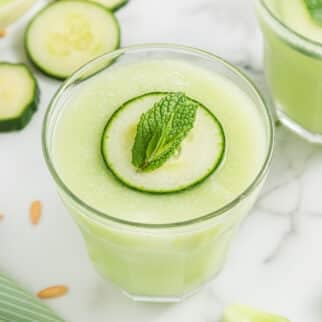 cucumber green smoothie in pretty glass on table.